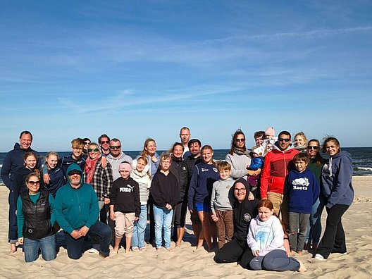 Gruppe von Menschen steht am Strand vor blauem Himmel