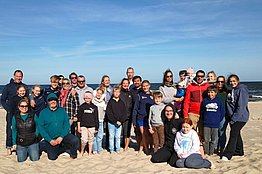 Gruppe von Menschen steht am Strand vor blauem Himmel
