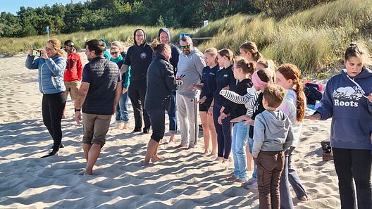 Gruppe von Menschen steht am Strand vor Dünenlandschaft