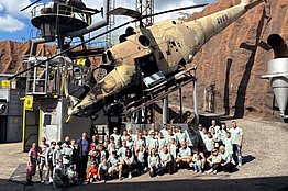 Gruppe von Menschen sitzt und steht vor einem großen, schräg gestellten Flugzeugwrack im Filmpark Babelsberg