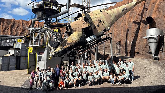 Gruppe von Menschen sitzt und steht vor einem großen, schräg gestellten Flugzeugwrack im Filmpark Babelsberg